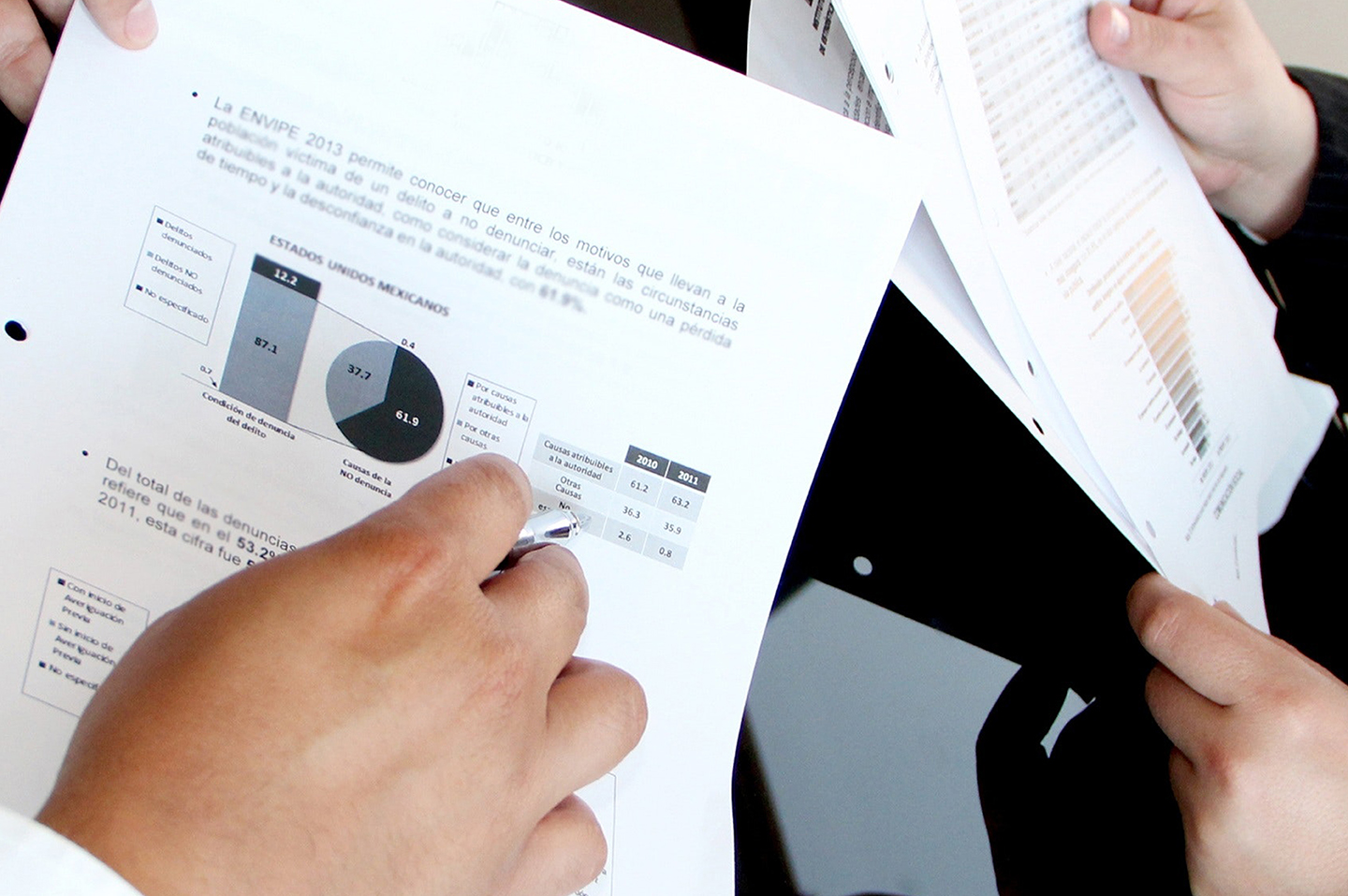 image of someone holding a sheet of paper with a pie chart and copy on it sitting next to someone who is also holding a packet of paper with a chart on it