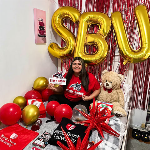A student in their dorm room that is decorated with Stony Brook gear