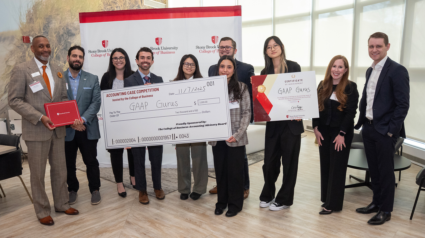 Students posing with a large ceremonial check at an accounting case competition