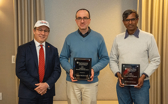 Excellence in Diversity Leadership Three men stand together indoors, smiling. The two on the right hold plaques. They're dressed in business casual attire, conveying a celebratory mood.